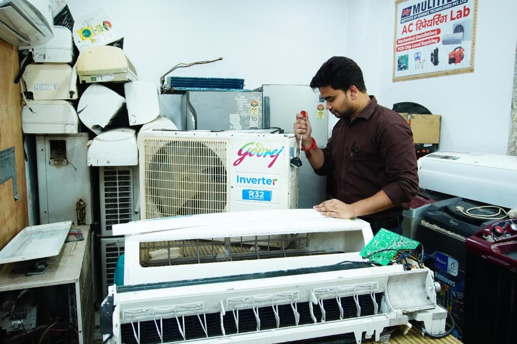 A technician repairing an air conditioner in a local service workshop