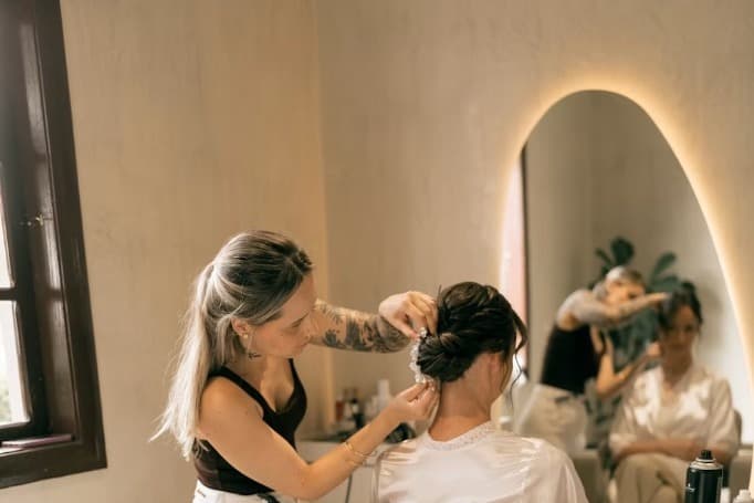 A stylist arranging a client's hair in a salon chair