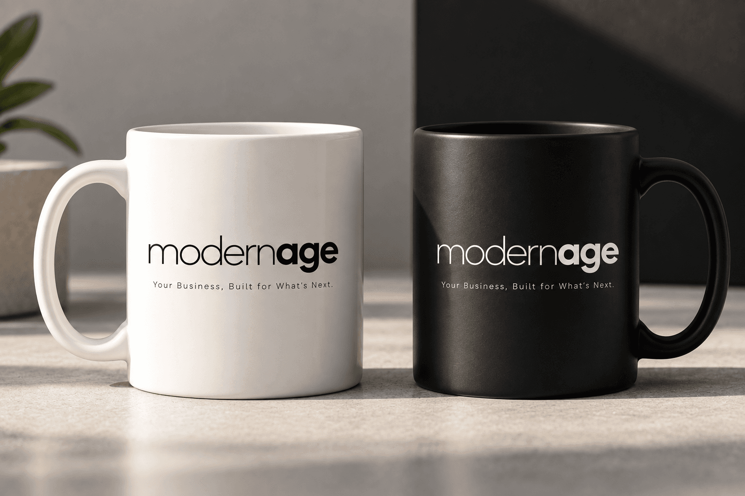 White and black mugs printed with the Modern Age wordmark, in studio light